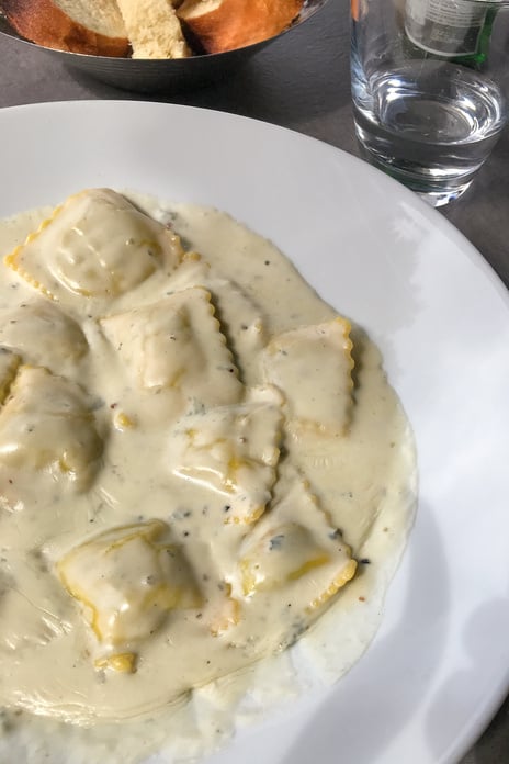 Ravioli in a cream sauce in a white plate